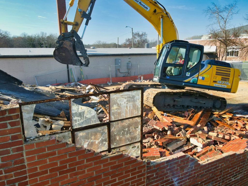 Excavator performing controlled building demolition